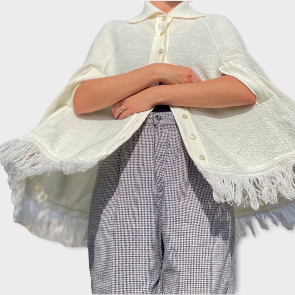 True vintage 1970s cream knit cape with fringe hem.